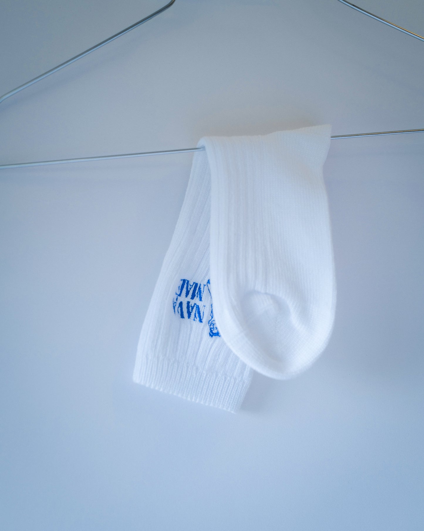 Nava Mae socks hangin on a metal hanger