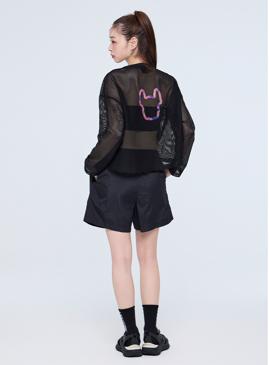 Person wearing a black outfit with a sheer overlay on a white background