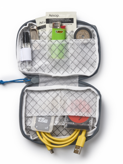 Open travel organizer pouch that can  contain various items including a bottle, hiking accessories, and cables 