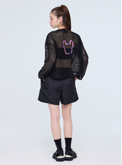 Person wearing a black outfit with a sheer overlay on a white background